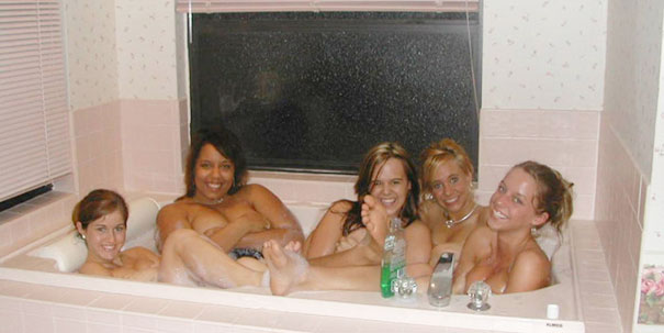 Group of five women smiling and sitting together in a bathtub, creating a surprising and funny moment.
