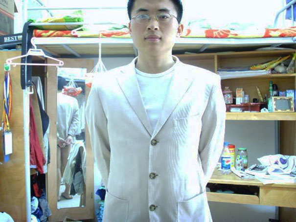 Man in a white jacket standing in a room, with a hidden reflection seen in the mirror, creating a surprising illusion.