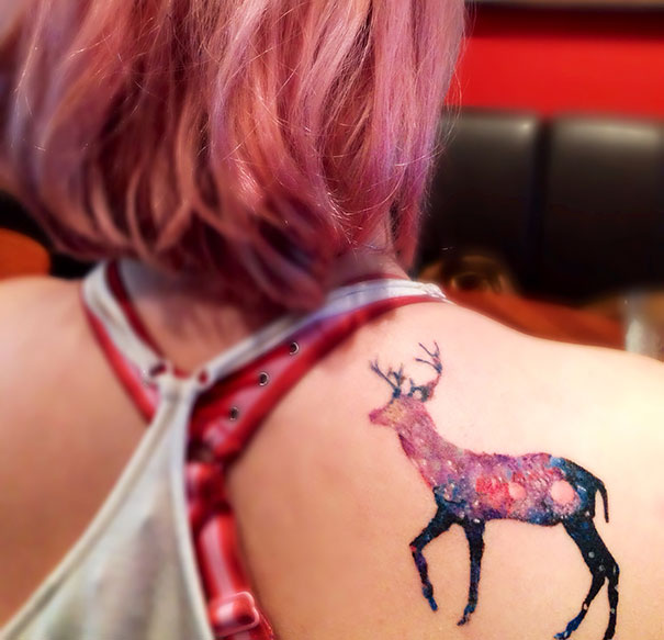 Colorful cosmic deer tattoo on back, perfect for astronomy lovers.