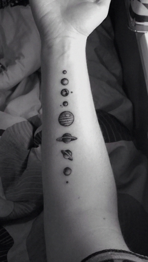 Arm tattoo with small planets, ideal for astronomy lovers.
