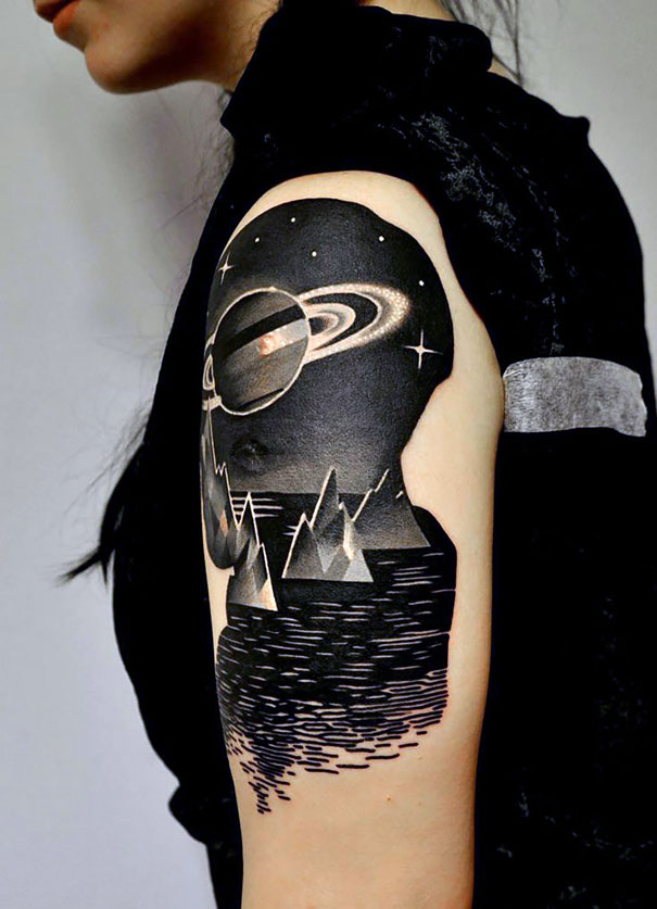 Arm with a cosmic tattoo featuring a planet and stars, ideal for astronomy lovers.