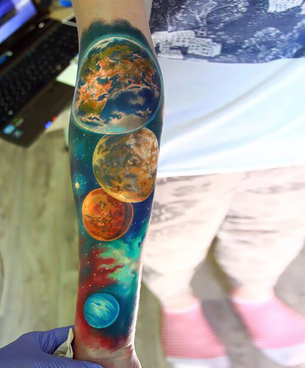 Colorful cosmic tattoo of planets on an arm, perfect for astronomy lovers.