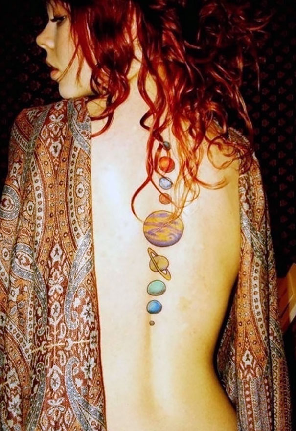 Colorful cosmic tattoo featuring planets on back, perfect for astronomy lovers.
