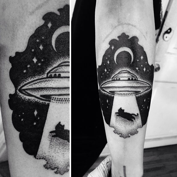 Creative cosmic arm tattoo with UFO and cat being abducted under a starry sky.
