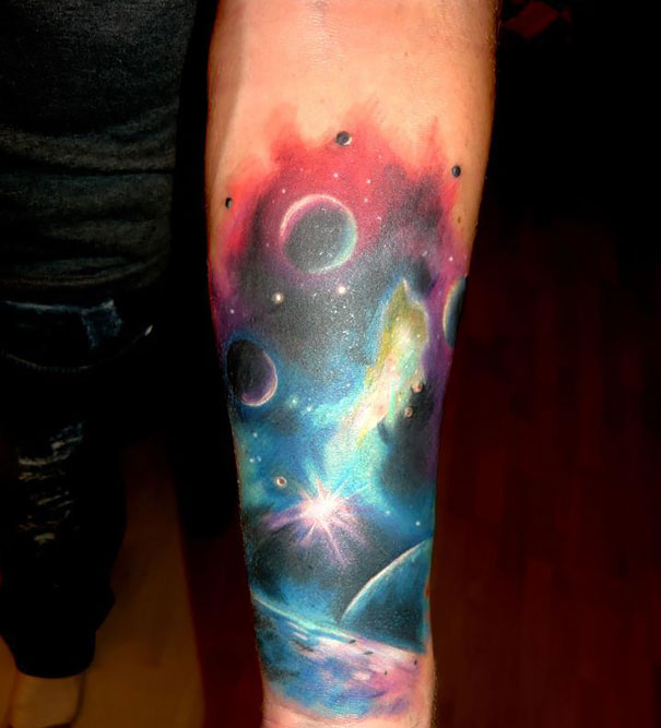 Colorful cosmic tattoo on arm featuring planets and galaxies for astronomy lovers.
