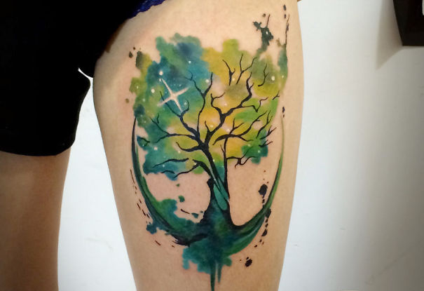 Colorful cosmic tree tattoo on a leg, featuring vibrant shades of green and blue, perfect for astronomy enthusiasts.