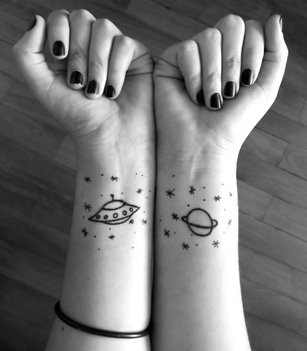 Space-themed wrist tattoos with a planet and spaceship design for astronomy lovers.