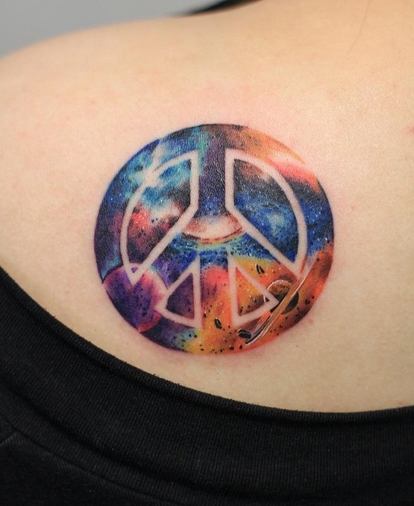 Colorful space-themed peace sign tattoo on a back, ideal for astronomy lovers.