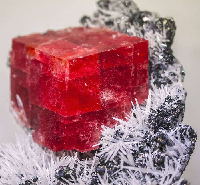 Beautiful minerals: vibrant red cube surrounded by white and black crystal formations.