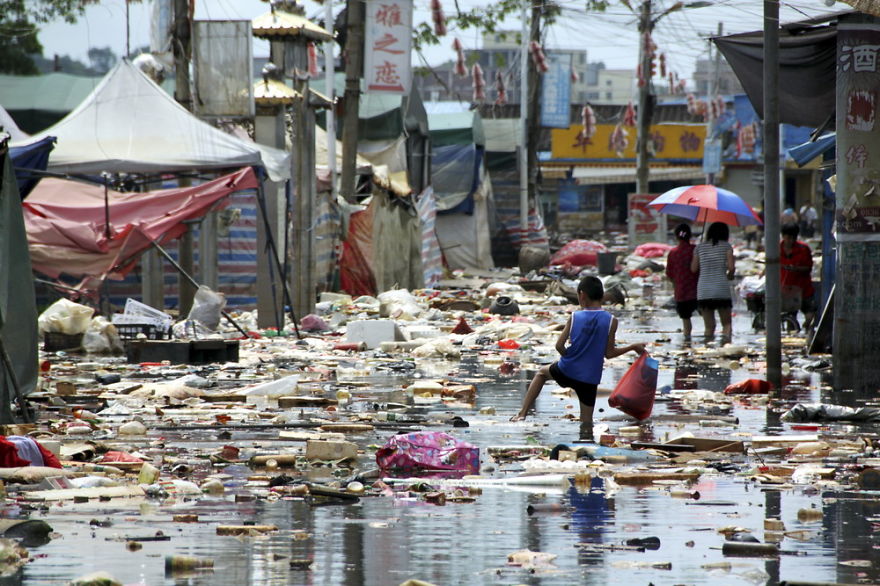 Boy Tries To Avoid Scattered Rubbish Floating On A Flooded Street In Shantou, Guangdong Province