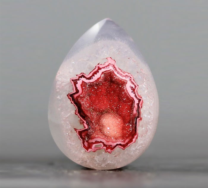 Beautiful mineral with a pear-shaped design featuring vibrant red and pink crystal formations.
