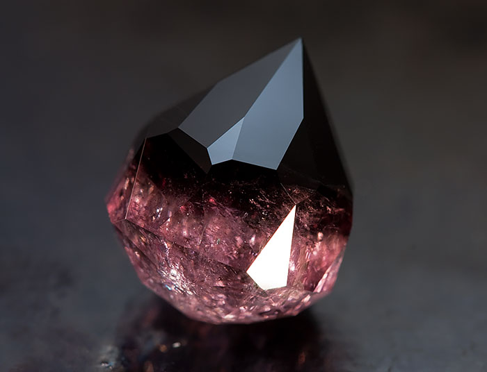 A stunning mineral with a dark, reflective surface and deep maroon hues.