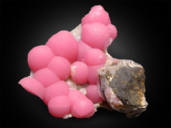 Bright pink mineral rhodochrosite with a contrasting rock background, highlighting beautiful stones and minerals.