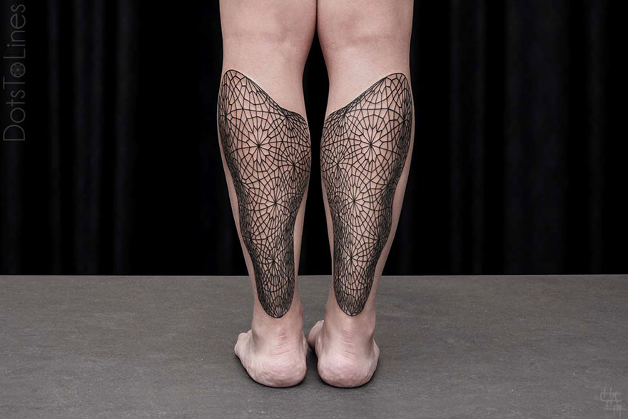 Geometric line tattoos by Chaim Machlev flow elegantly on calves against a dark background.