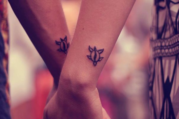 Matching couple tattoos on arms, symbolizing love and commitment.