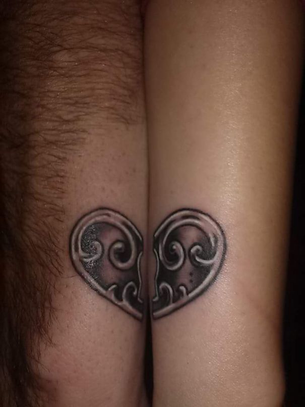 Matching couple tattoos forming a heart on arms.