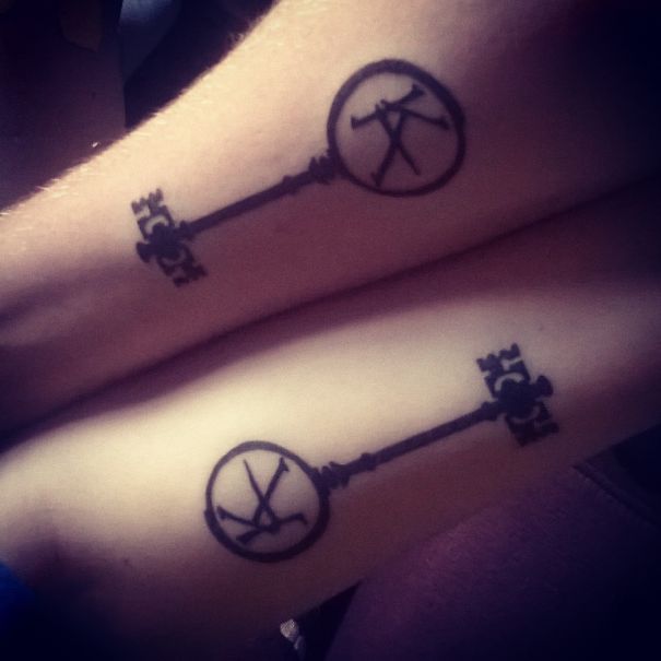 Matching couple tattoos of vintage keys on forearms, symbolizing lasting love.