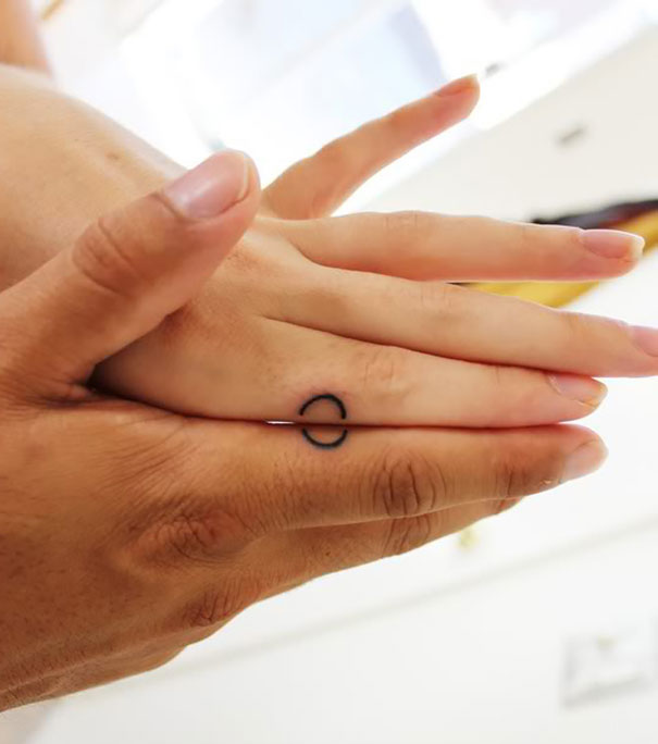 Two hands holding, with a matching couple tattoo on fingers, symbolizing lifelong love.