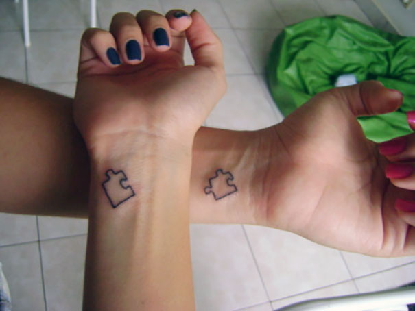 Matching couple tattoos of puzzle pieces on wrists, symbolizing unity and connection for lovers.