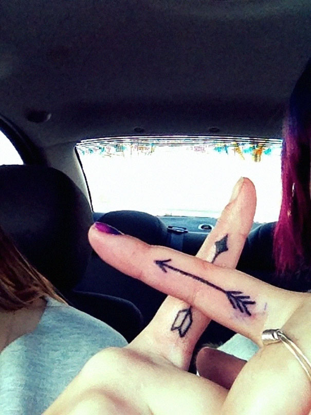 Couple's fingers with matching arrow tattoos symbolizing their journey together.