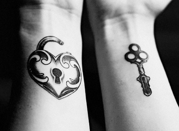 Matching couple tattoos of a heart-shaped lock and key on wrists, symbolizing eternal love.