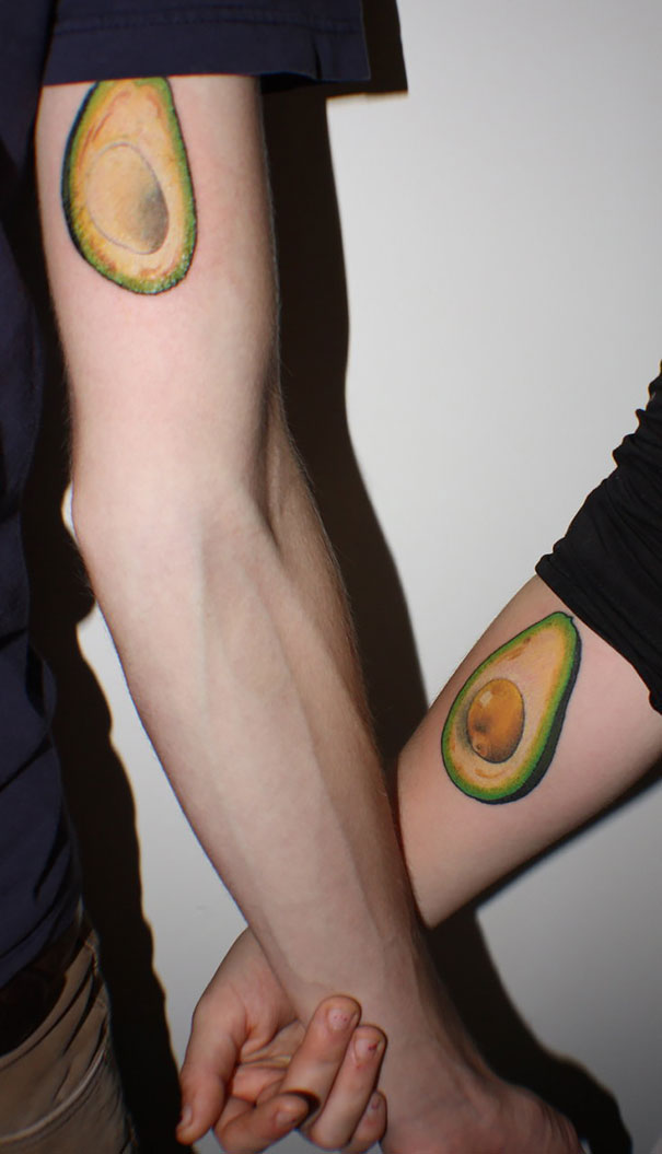 Matching couple tattoos of avocado halves on forearms, symbolizing love growing old together.