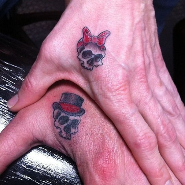 Matching couple tattoos featuring skulls with a bow and top hat.
