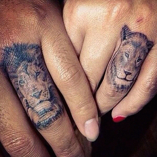 Matching couple tattoos with lion designs on fingers, symbolizing love and togetherness.