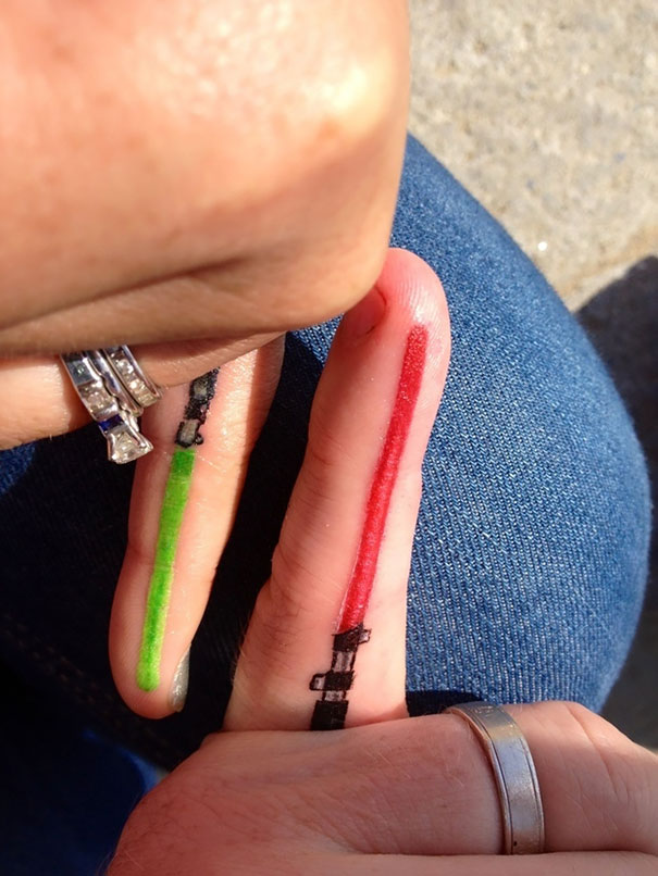 Couple matching tattoos with red and green lightsabers on fingers.