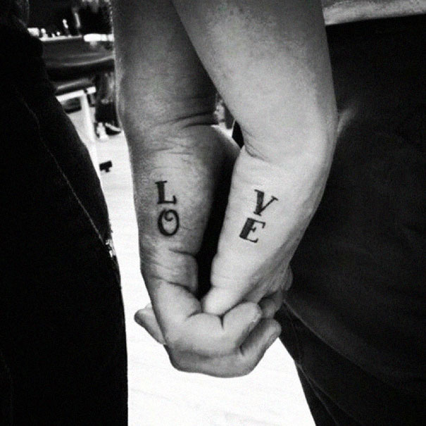 Couple tattoos of the word "LOVE" on joined hands, symbolizing lasting commitment.