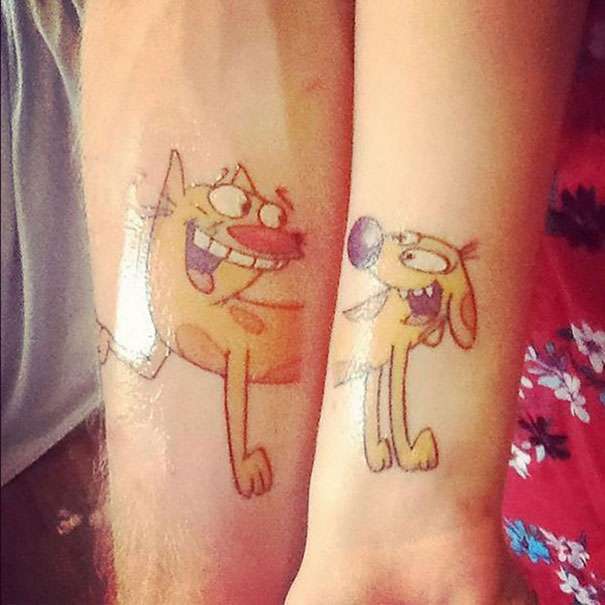 Cartoon dog and cat matching couple tattoos on two arms.