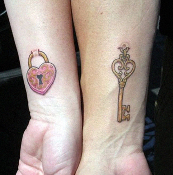 Matching couple tattoos: ornate key and pink heart lock on forearms.