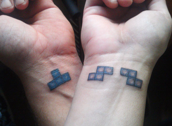 Matching couple tattoos of Tetris pieces on wrists, symbolizing unity and love for a lasting relationship.