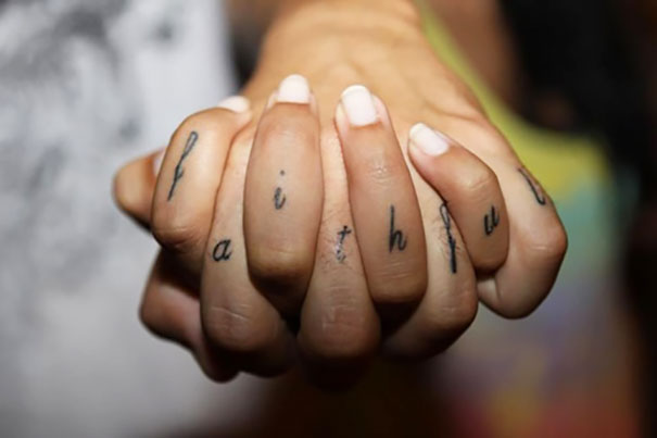 Couple displaying matching "faithful" tattoos on their fingers, symbolizing love and unity.