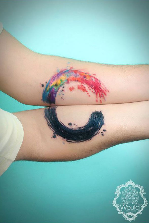 Matching couple tattoos with colorful and black watercolor designs on forearms.