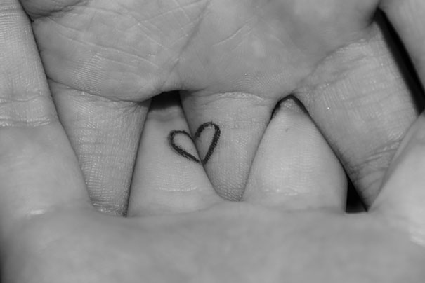 Matching couple tattoo of a heart on two hands, symbolizing love and unity.