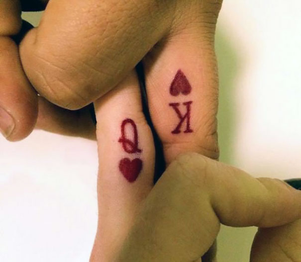 Matching couple tattoos of king and queen of hearts on fingers.