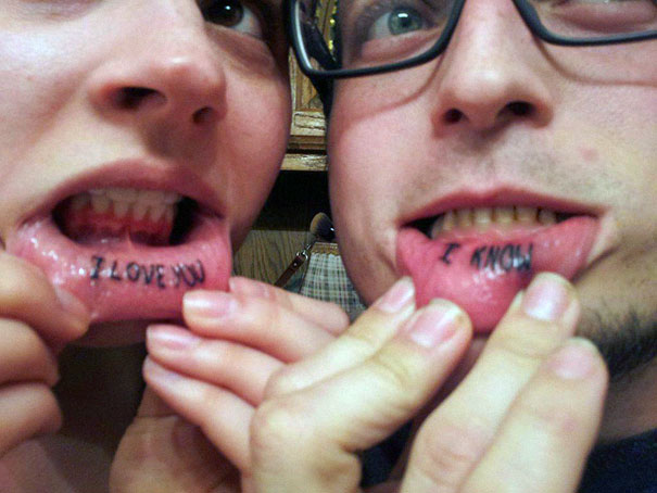Couple showing matching tattoos with "I love you" and "I know" on their inner lips, symbolizing lasting love.