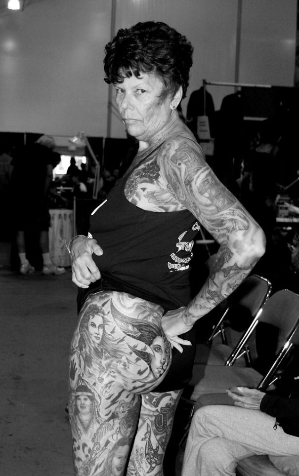 Senior woman with tattoos on arms and thighs at a convention, showcasing how ink looks on mature skin.