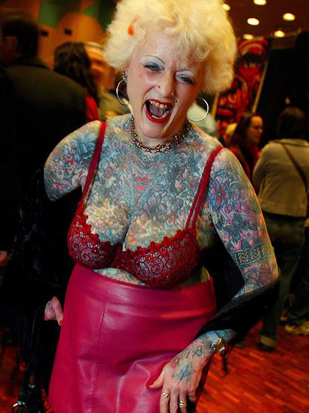 Senior woman proudly displaying vibrant tattoos at an event, showcasing how ink can look at 60.