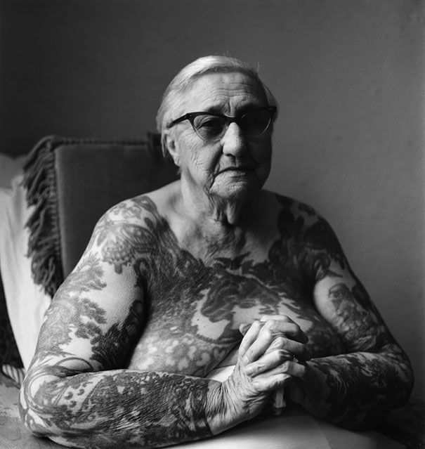 Senior with tattoos, sitting in chair, showcases inked skin with proud expression, answering how tattoos look at 60.