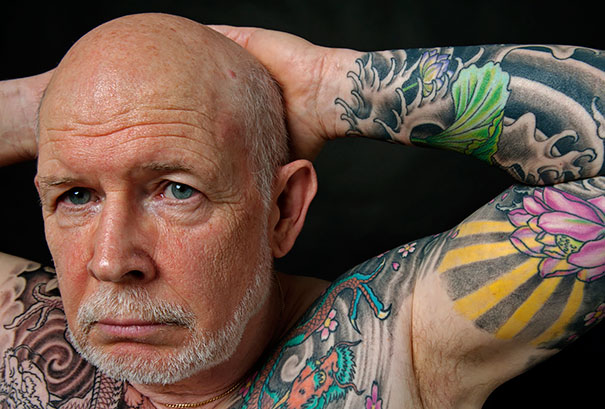 Senior man with colorful tattoos on arms and chest, showcasing how ink looks at 60.