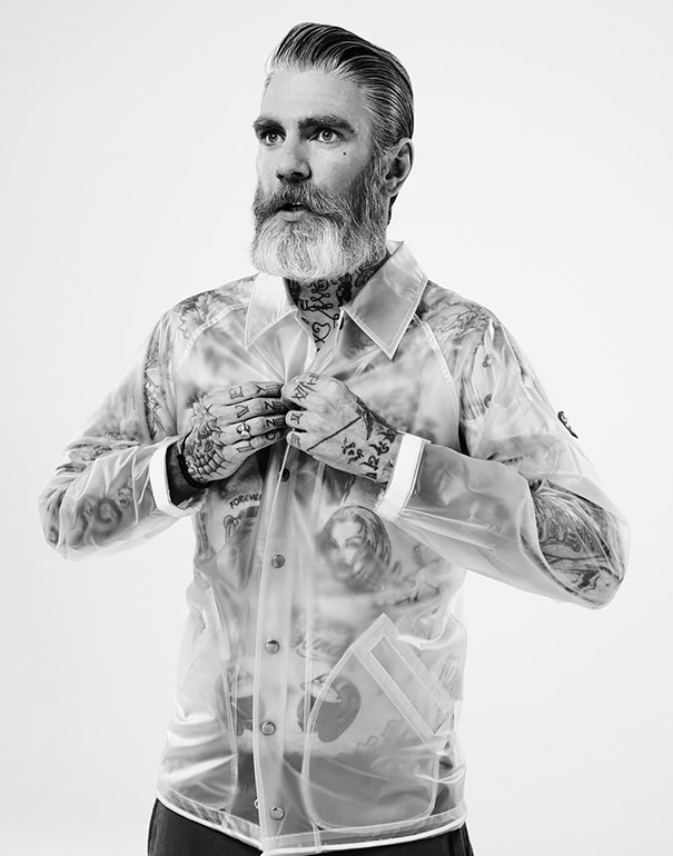 Senior man with tattoos wearing a sheer jacket, showcasing inked skin at age 60.
