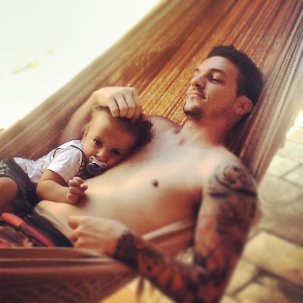 Tattoos and babies: A tattooed parent cuddles with their child in a hammock, creating a beautiful scene together.