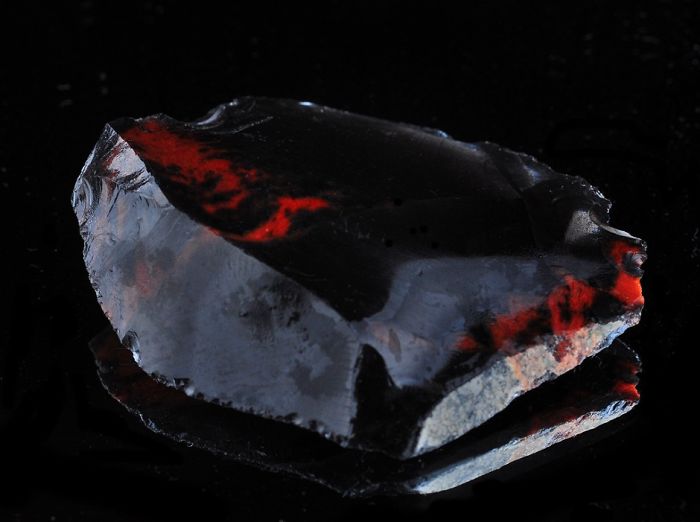 A stunning mineral with dark and red hues against a black background.