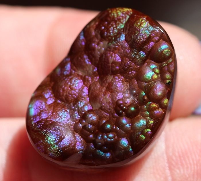 Beautiful iridescent mineral showing vibrant colors on a hand.