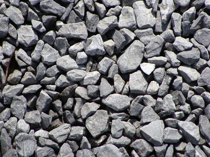 A collection of numerous small, gray minerals and stones closely arranged together.