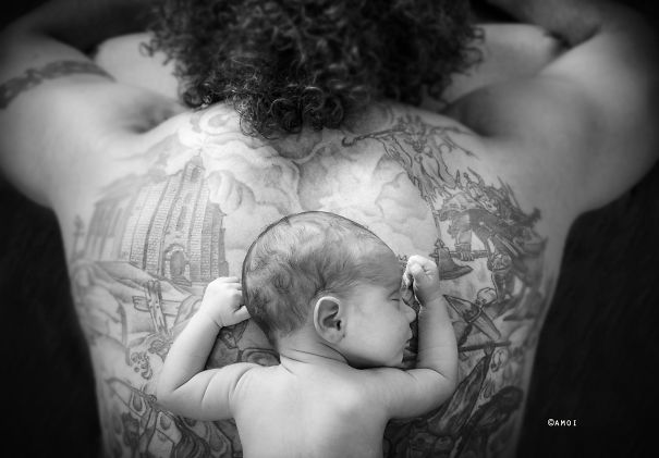 Baby resting on tattooed parent's back, depicting a beautiful connection between babies and their tattooed parents.