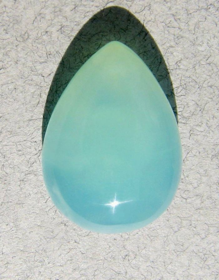 A polished, oval blue mineral stone with a glossy surface reflecting light.