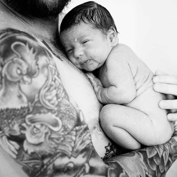 Baby cuddling with tattooed parent, capturing a beautiful bond.